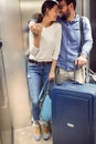 Smiling travelers couple with suitcases in lift