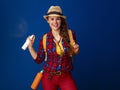 Smiling traveller woman on blue background with bottle of spray