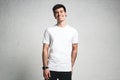 Smiling trendy guy wearing blank white t-shirt, horizontal studio portrait