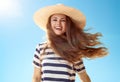 Smiling trendy woman with fluttering hair against blue sky Royalty Free Stock Photo