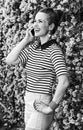 Smiling trendy woman near flowers bed speaking on cell phone