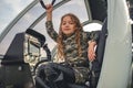 Smiling tween girl in camouflage dress sitting in helicopter cockpit