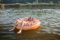 Girl relaxes on big donut inflatable ring on lake on hot summer day, happy summertime, countryside Royalty Free Stock Photo