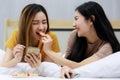 Smiling Two Asian young women lovely couple repose on white bed and happy Feed apples. Funny women together on cozy. Concept In