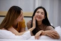 Smiling Two Asian young women lovely couple repose on white bed and happy. Women using my hands to massage my face. Concept In Royalty Free Stock Photo