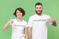 Smiling two friends couple in white volunteer t-shirt isolated on green background. Voluntary free work assistance help