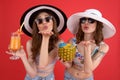 Smiling two women drinking cocktails blowing kisses. Royalty Free Stock Photo