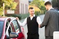 Smiling Valet And Businessperson Standing Near Car