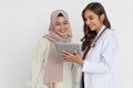 smiling veiled woman and doctor beautiful woman laughing while using tablet together