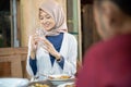 a smiling veiled woman holding a glass while drinking for iftar
