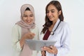 smiling veiled woman with pointing hand and happy beautiful female doctor while using tablet together