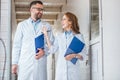 smiling vets in white coats walking with clipboards in veterinary clinic and looking at each other Royalty Free Stock Photo