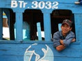 Smiling vietnamese fisherman at his wooden boat