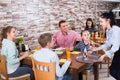 Smiling wairtress is bringing delicious dessert to young visitors Royalty Free Stock Photo