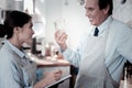 Smiling waiter looking at his colleague and holding a glass