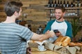 Smiling waiter receiving credit card of customer for payment at counter Royalty Free Stock Photo
