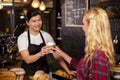 Smiling waiter serving a coffee to a customer Royalty Free Stock Photo