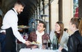 Waiter serving guests at terrace restaurant Royalty Free Stock Photo