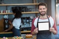 Smiling waiter showing digital tablet at counter in cafÃÂ©