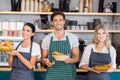 Smiling waiter and two waitresses holding plate of bread rolls Royalty Free Stock Photo