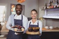 Smiling waiter and waitress holding desserts at counter Royalty Free Stock Photo