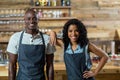 Smiling waiter and waitress standing against counter in cafÃÂ©