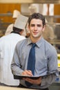 Smiling waiter writing in folder