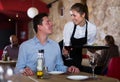 Smiling waitress bringing delicious meal to young man