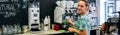 Smiling waitress cleaning coffee maker