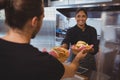 Smiling waitress giving baskets with food to coworker Royalty Free Stock Photo