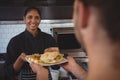 Smiling waitress giving plate with food to coworker Royalty Free Stock Photo