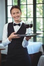 Smiling waitress holding a tray with glasses of red wine Royalty Free Stock Photo
