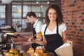 Smiling waitress putting bread roll in paper bag Royalty Free Stock Photo
