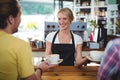 Smiling waitress serving cup of coffee to customer Royalty Free Stock Photo