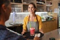 Smiling waitress serving strawberry smoothie