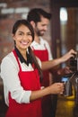Smiling waitress steaming milk at the coffee machine Royalty Free Stock Photo