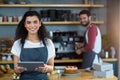Smiling waitress using digital tablet at counter in cafÃÂ© Royalty Free Stock Photo