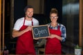 Smiling waitress and waiter standing with open sign board outside cafÃÂ© Royalty Free Stock Photo