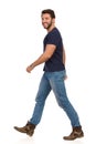 Smiling Walking Man In Blue T-shirt, Jeans And Boots. Side View Royalty Free Stock Photo