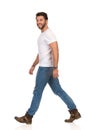 Smiling Walking Man In White T-shirt, Jeans And Boots Is Looking At Camera Royalty Free Stock Photo