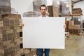 Smiling warehouse worker holding large white poster Royalty Free Stock Photo