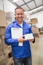 Smiling warehouse worker holding small box and clipboard Royalty Free Stock Photo