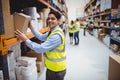 Smiling warehouse worker taking package in the shelf Royalty Free Stock Photo