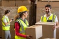 Smiling warehouse workers carrying a cardboard box Royalty Free Stock Photo