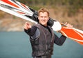 Look at that guy there. Smiling water-skier holding his skis alongside the lake and pointing.