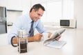 Smiling well dressed man with coffee cup reading newspaper in kitchen Royalty Free Stock Photo