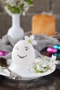 Smiling white egg and flowers on clay plate. Happy Easter card. Holidays breakfast concept. Festive table place setting decoration Royalty Free Stock Photo