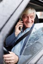 Smiling white haired senior man speaking by phone inside car Royalty Free Stock Photo