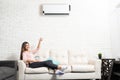 Smiling Woman Is Adjusting Temperature Of Air Conditioner Royalty Free Stock Photo