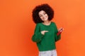 Smiling woman with Afro hairstyle wearing green casual style sweater holding and pointing at red